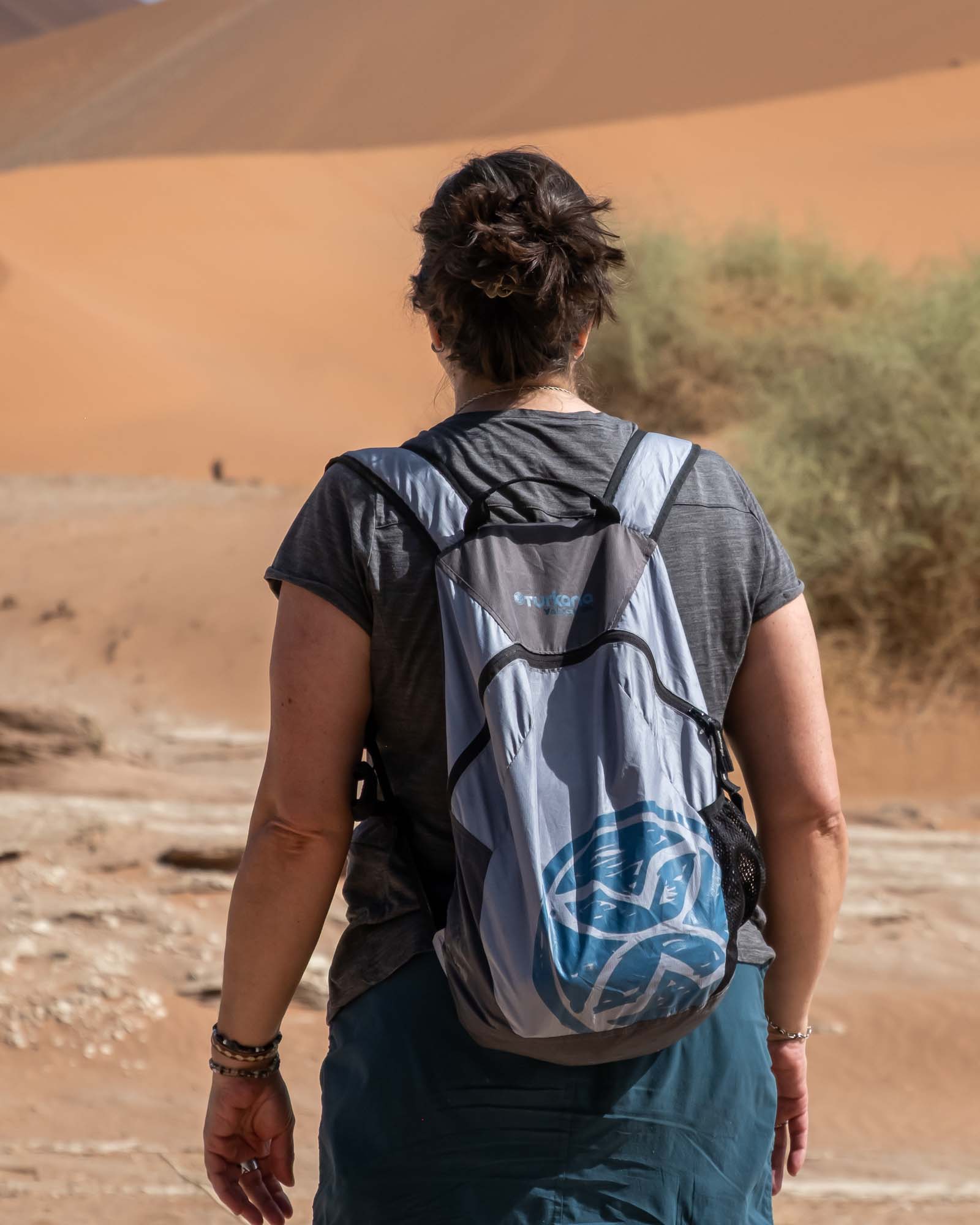 Turkana YakSak 15L packable backpack worn on a desert hike with dunes in the background.
