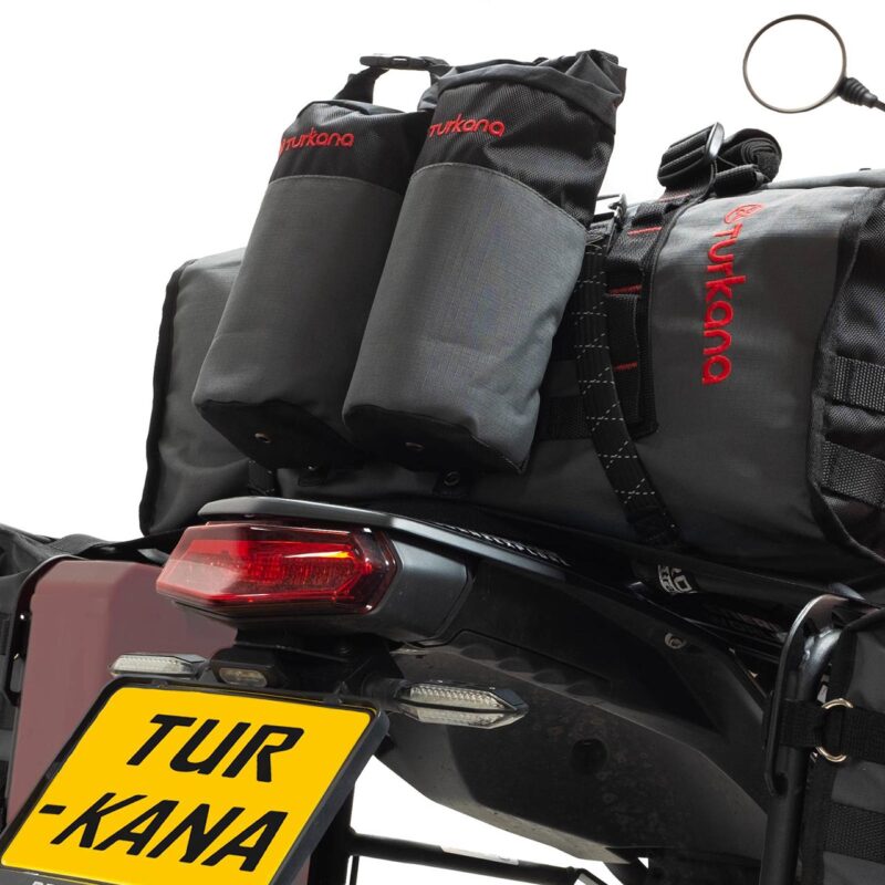 Turkana Duffalo duffel bag mounted on a motorcycle with Oxpacker pouches attached via MOLLE webbing.
