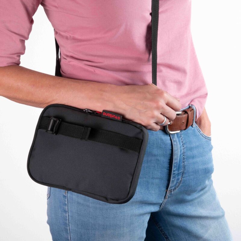 Person wearing the black Turkana SlingThing cross body pouch, showing the front cam buckle strap and compact fit against the hip.