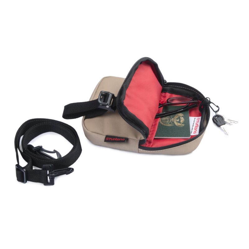 Open Turkana SlingThing pouch showing red interior divider, key ring, passport, glasses, and keys inside.