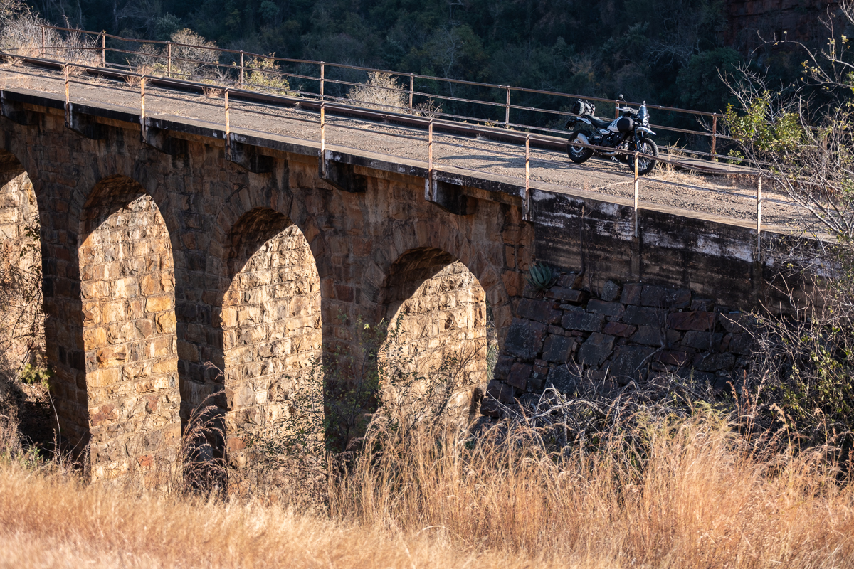 Royal Enfield Himalayan 450 adventure motorcycle parked on a historic railway bridge during an overland ride in South Africa. Featured with lightweight Turkana Gear motorcycle luggage.