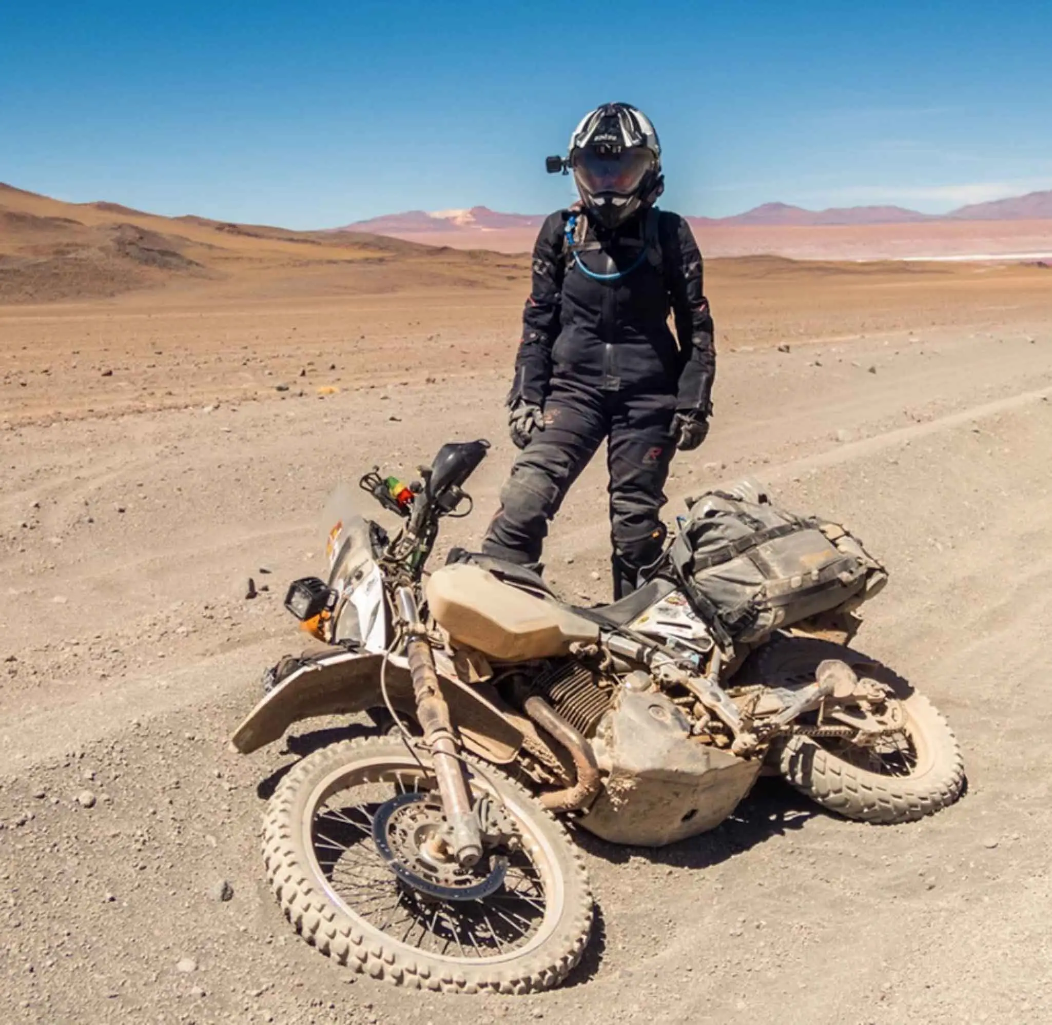 Adventure rider beside a fallen dual-sport motorcycle fitted with Turkana Avvida saddlebags in a remote desert.