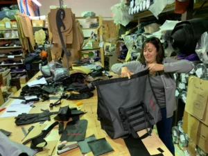 Turkana Gear product designer inspecting a grey motorcycle duffel waterproof surrounded by patterns and materials in the workshop.