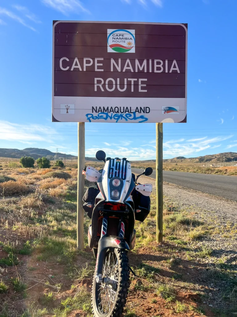 KTM 690 Enduro beneath the Cape Namibia Route sign in Namaqualand